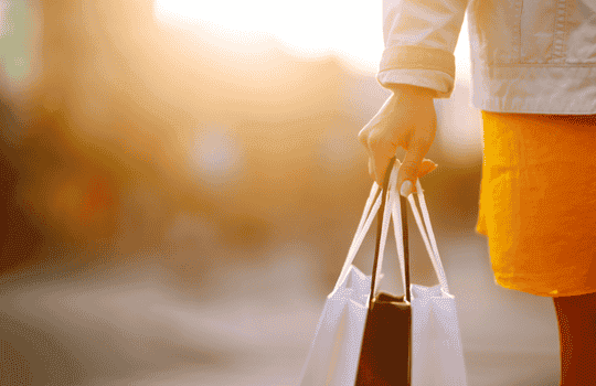 Persona saliendo de compras con bolsas, gracias a un préstamo rápido en línea en Turbocredito.co.
